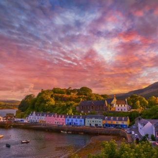 • Sunset over famous Quay Street in Portree, Isle of Skye, with golden hues and tranquil waters